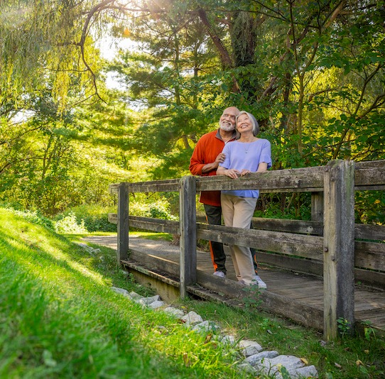 Smiling couple on walking path bridge enjoying nature