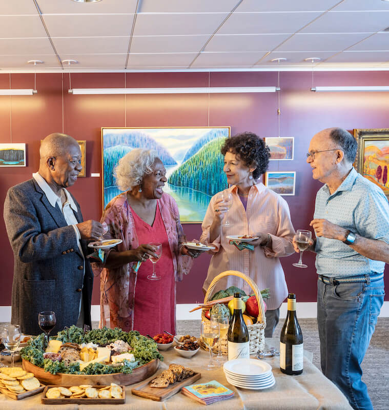 Group of seniors enjoying food and drinks at an art gallery reception