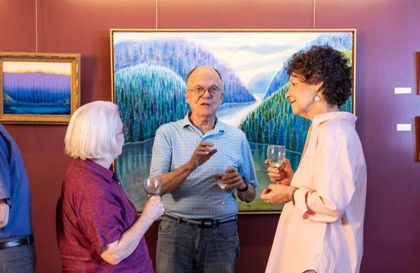 Two senior women and a senior man having a conversation at an art show reception