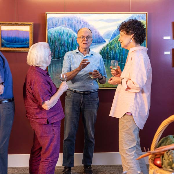 Two senior women and a senior man having a conversation at an art show reception