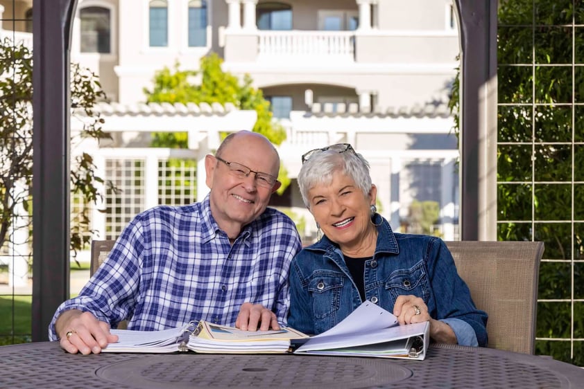 Senior couple sitting at a patio table with binders in front of them