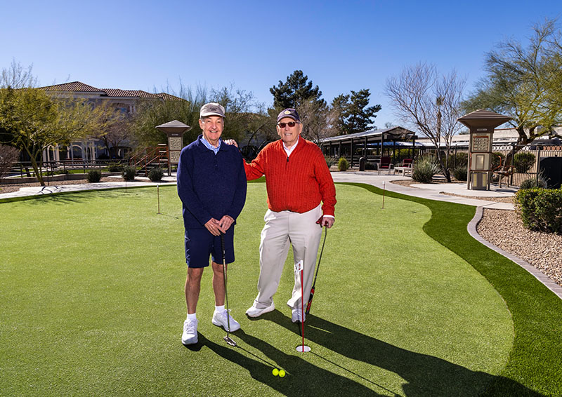 Two senior men smiling for photo on putting green