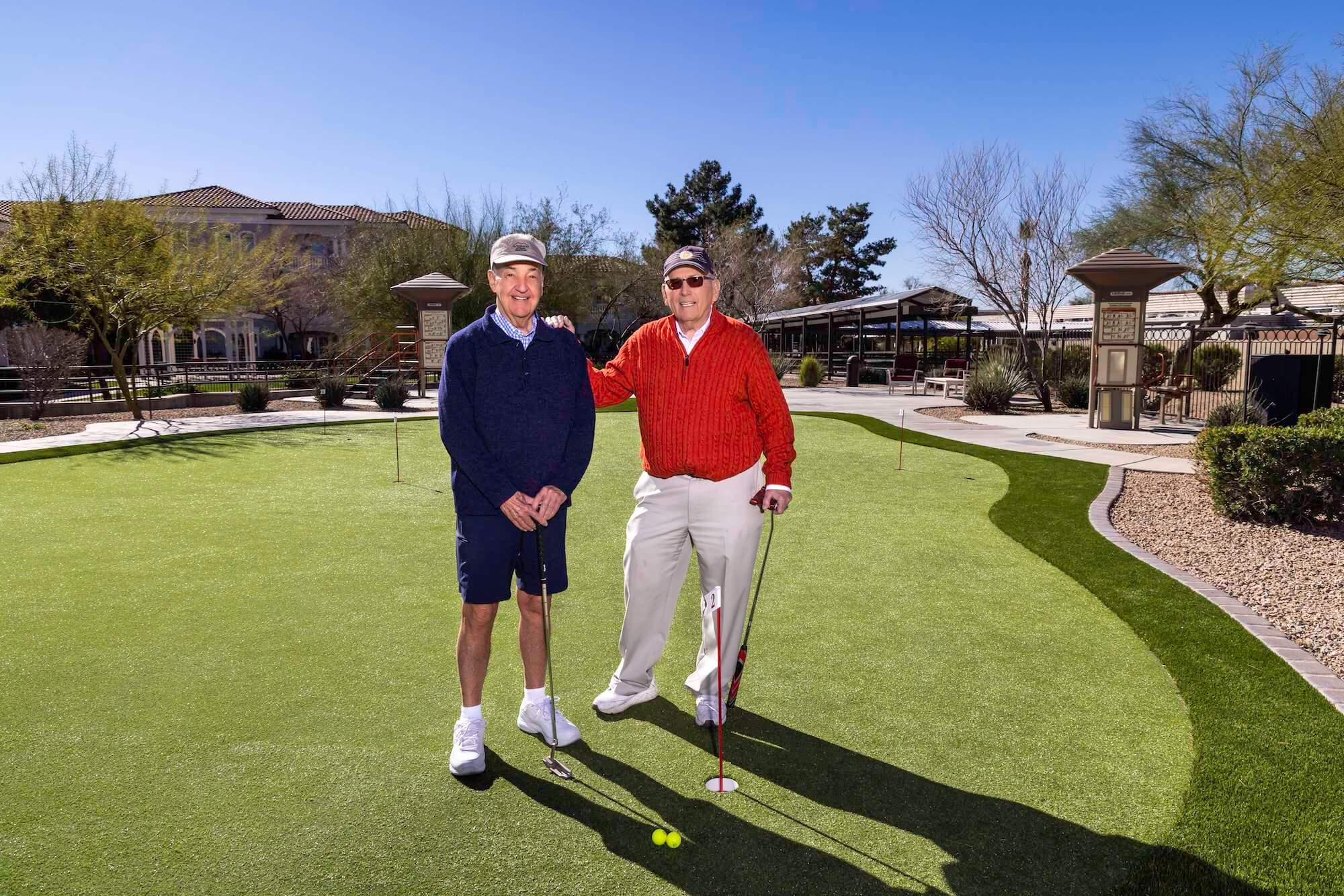 Two senior men smiling for photo on putting green