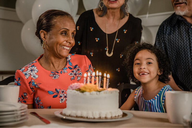 Senior woman celebrating her birthday with her granddaughter and other family