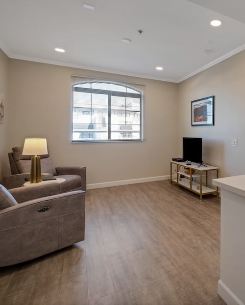 Living room of an apartment at The Terraces of Phoenix with two chairs and TV