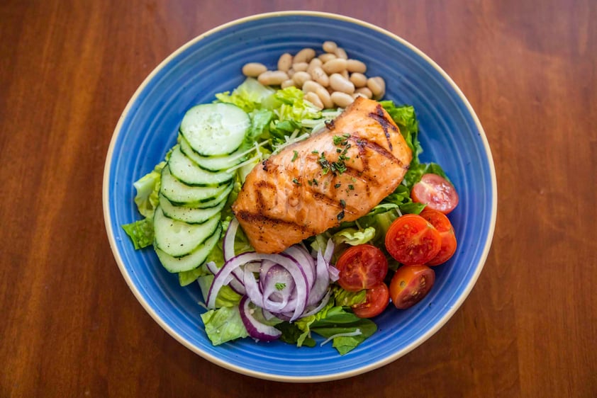 Grilled salmon on a bed of cucumbers, onion, beans and tomatoes 