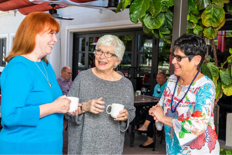Three senior women drinking coffee on a patio