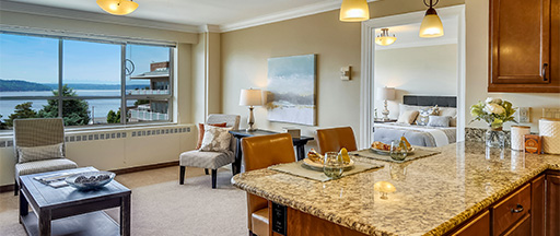 Living room and kitchen of an apartment at Judson Park with views of the Puget Sound outside of the windows