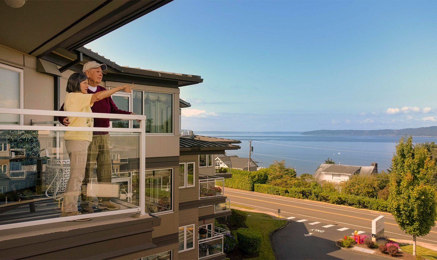 seniors standing on an apartment balcony overlooking the water