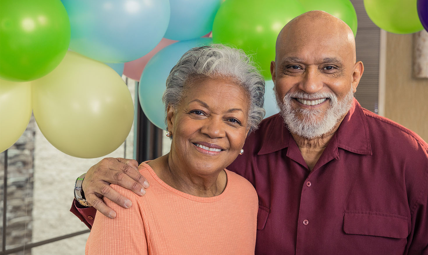 Senior man and woman at a birthday party with balloons in the background