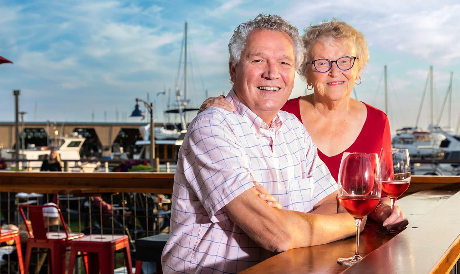 Senior couple enjoying a glass of red wine at a marina bar