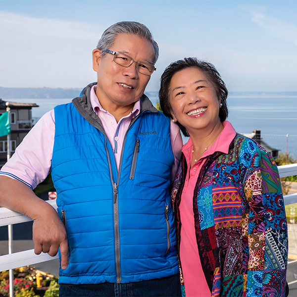 Smiling senior couple on a balcony at Judson Park overlooking the Puget Sound