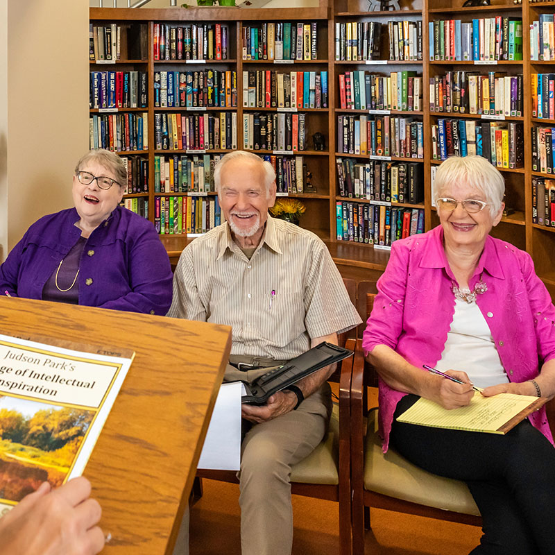 Two senior women and a senior man listening to a presentation in the library