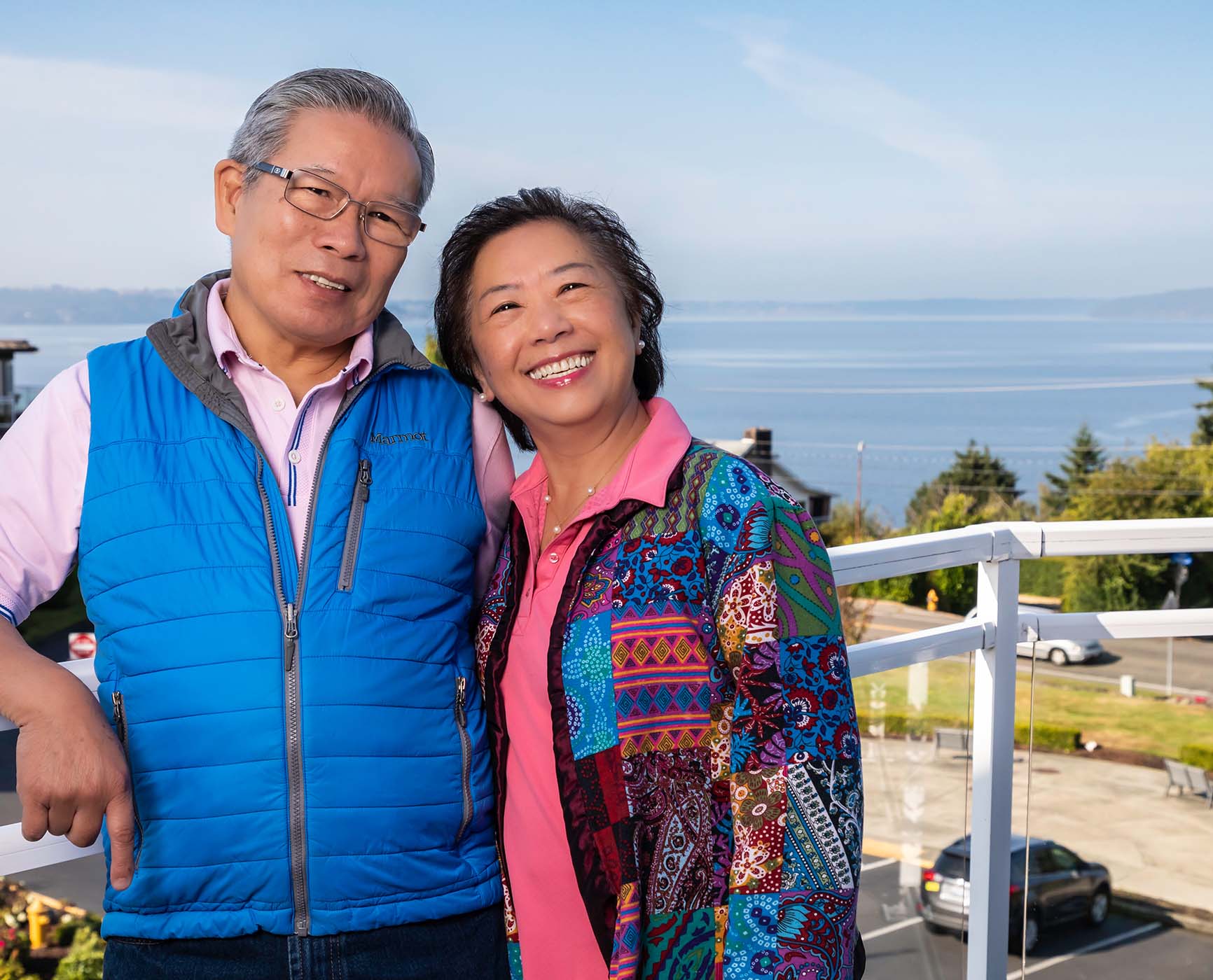 Smiling senior couple on a balcony at Judson Park overlooking the Puget Sound