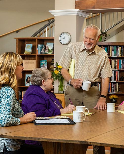 Group of seniors with mugs sitting in the community library