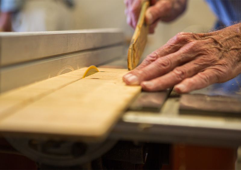 Close-up of a senior man's hands using a table saw