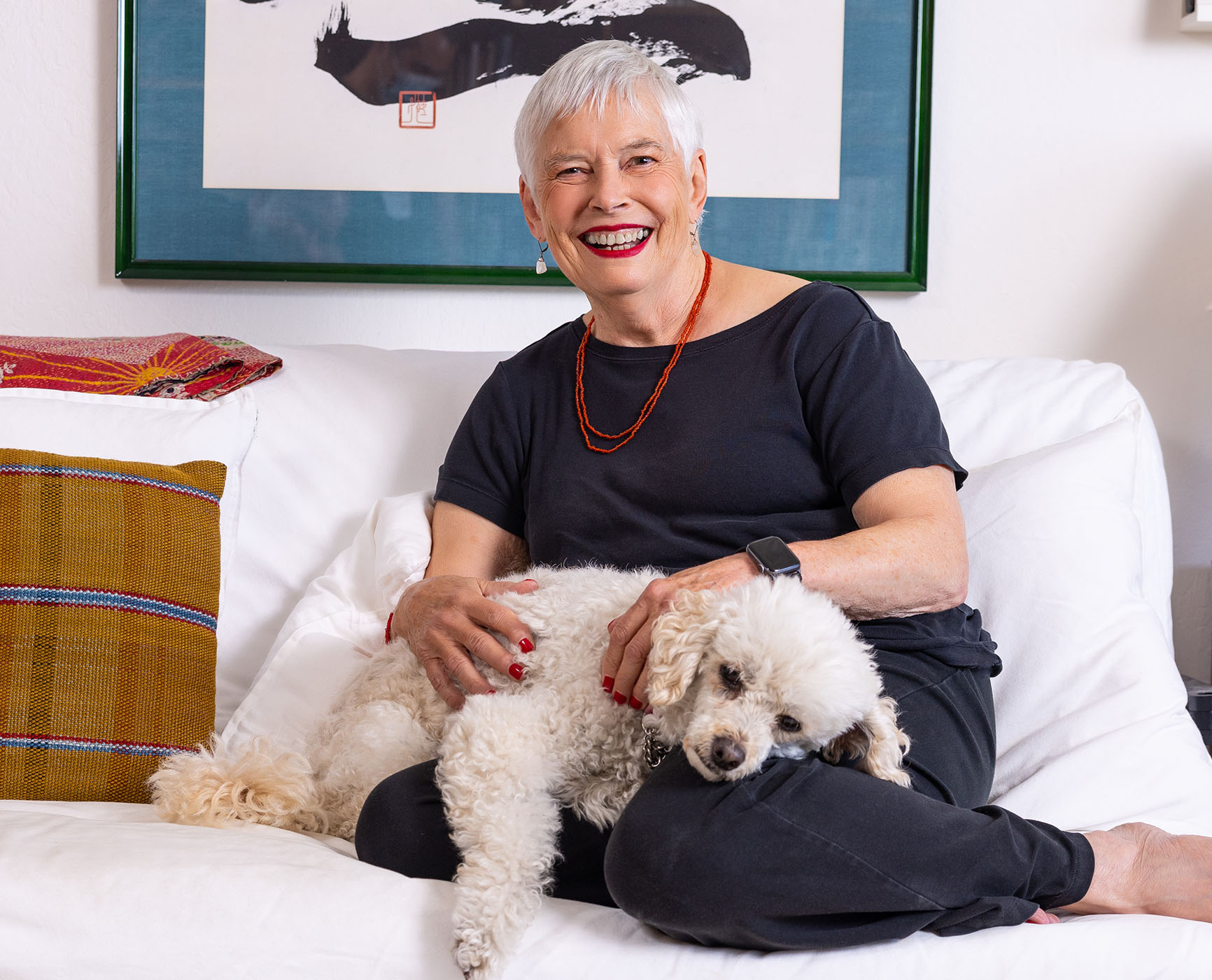 Senior woman sitting on a couch with a small white dog