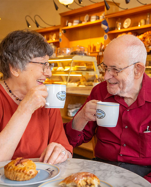 Senior couple enjoying coffee and pastries at the cafe at Piedmont Gardens