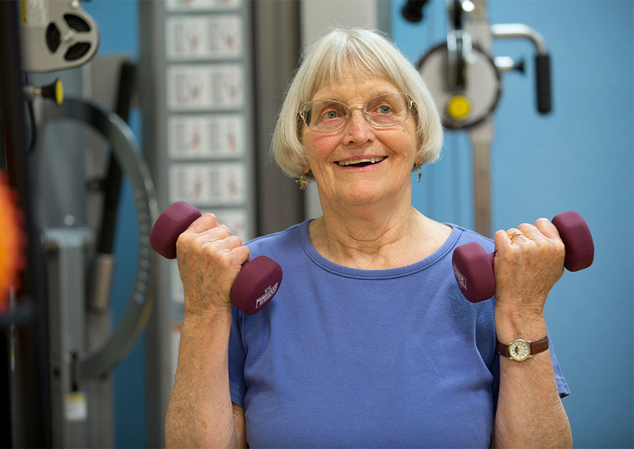 Senior woman lifting dumbbells in the Piedmont Gardens fitness center