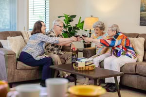 4 people doing cheers seated on 2 couches