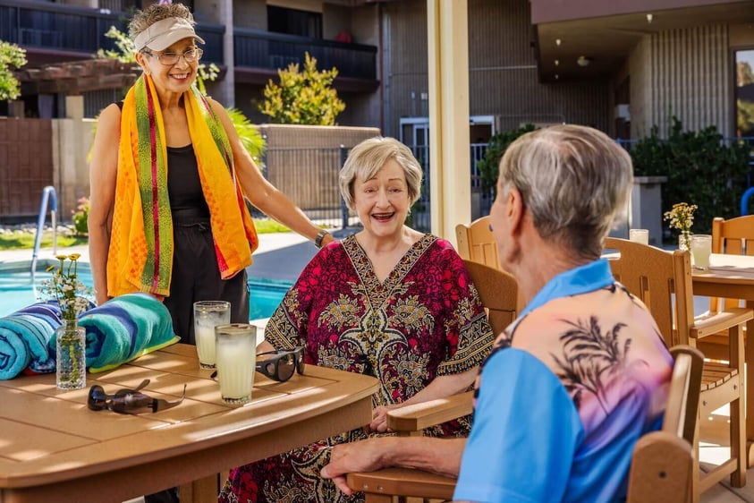 people relaxing a poolside table