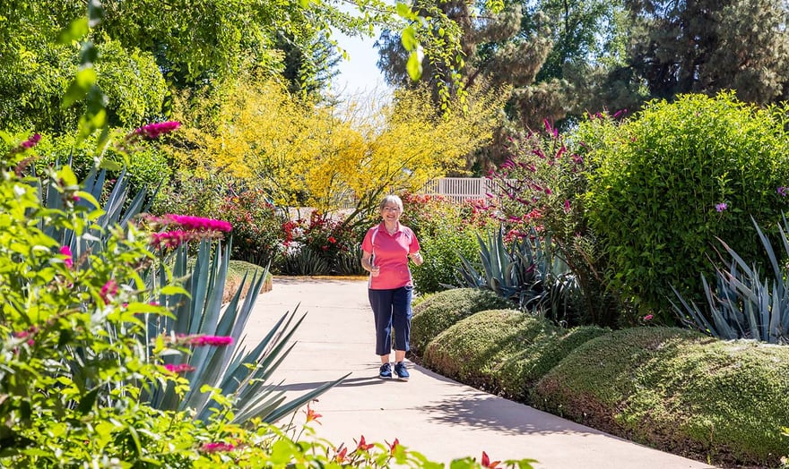 Senior woman walking on a sidewalk through the garden at Rosewood
