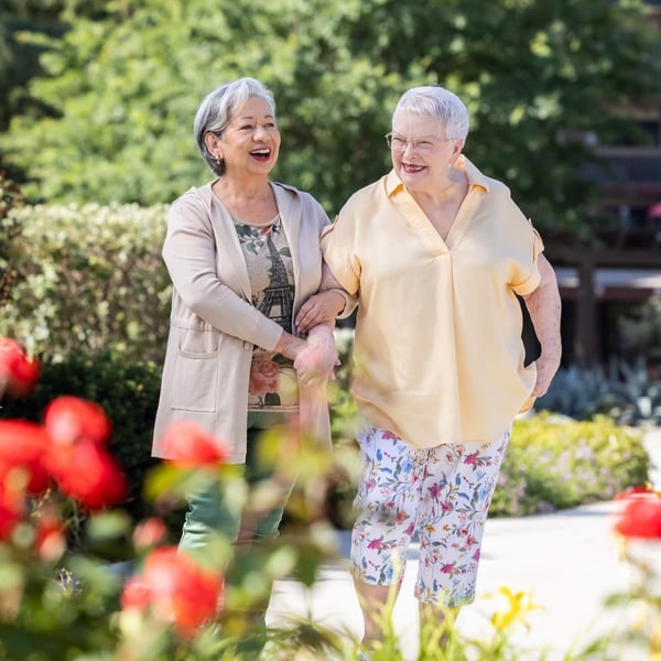 two women walking through a flower garden