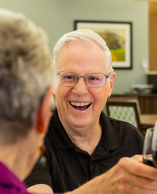 Senior man holding a glass of wine in the dining room at Rosewood