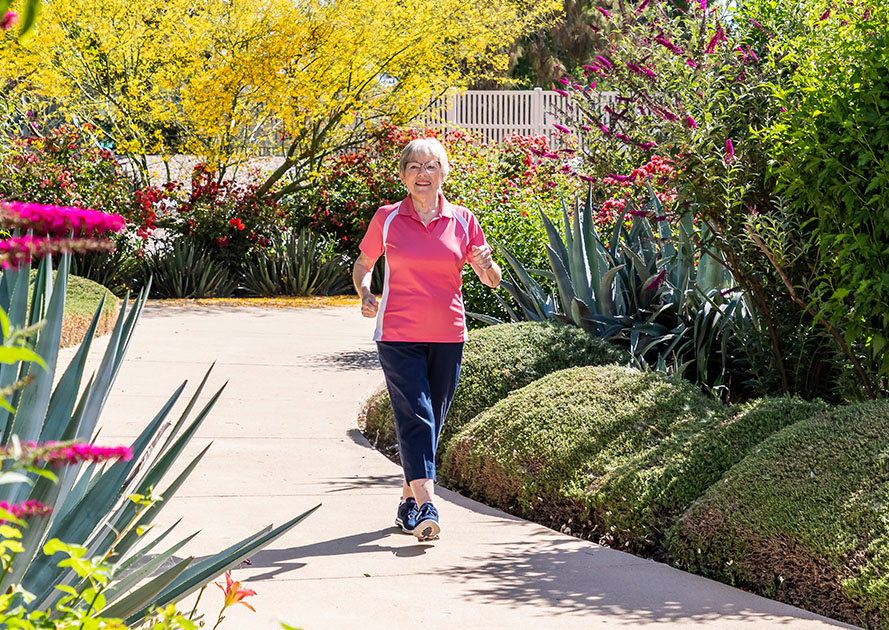 Senior woman walking on a sidewalk through the garden at Rosewood