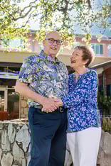Smiling senior couple wearing brightly patterned shirts hugging outside