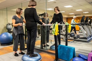 Senior woman standing on a BOSU ball in front of a mirror in the fitness center at Royal Oaks