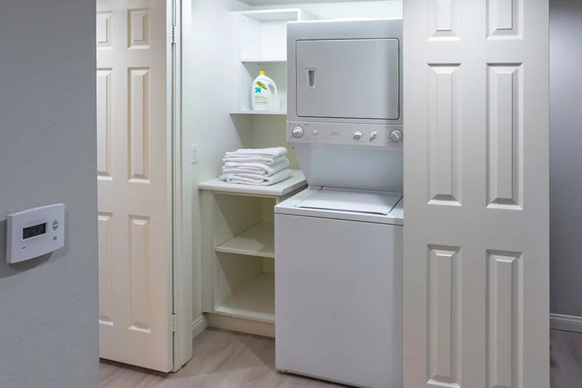 Laundry area featuring a stacked washer and dryer in an apartment at Royal Oaks