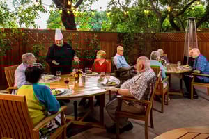 Royal Oaks chef speaking to a table of seniors dining on the patio at Royal Oaks