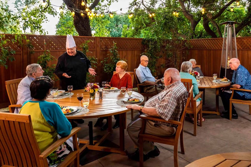 Royal Oaks chef speaking to a table of seniors dining on the patio at Royal Oaks