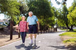 Senior couple holding hands and taking a walk on a paved path at Royal Oaks