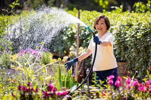 Senior woman watering flowers in the Royal Oaks gardens