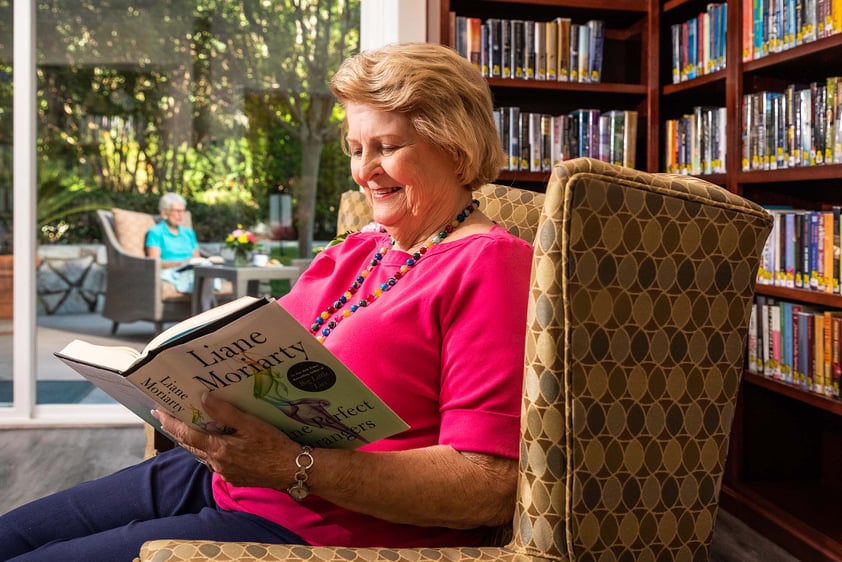 Senior woman sitting in an armchair reading the book 