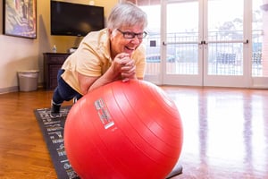 Senior woman using big red exercise ball in the fitness center