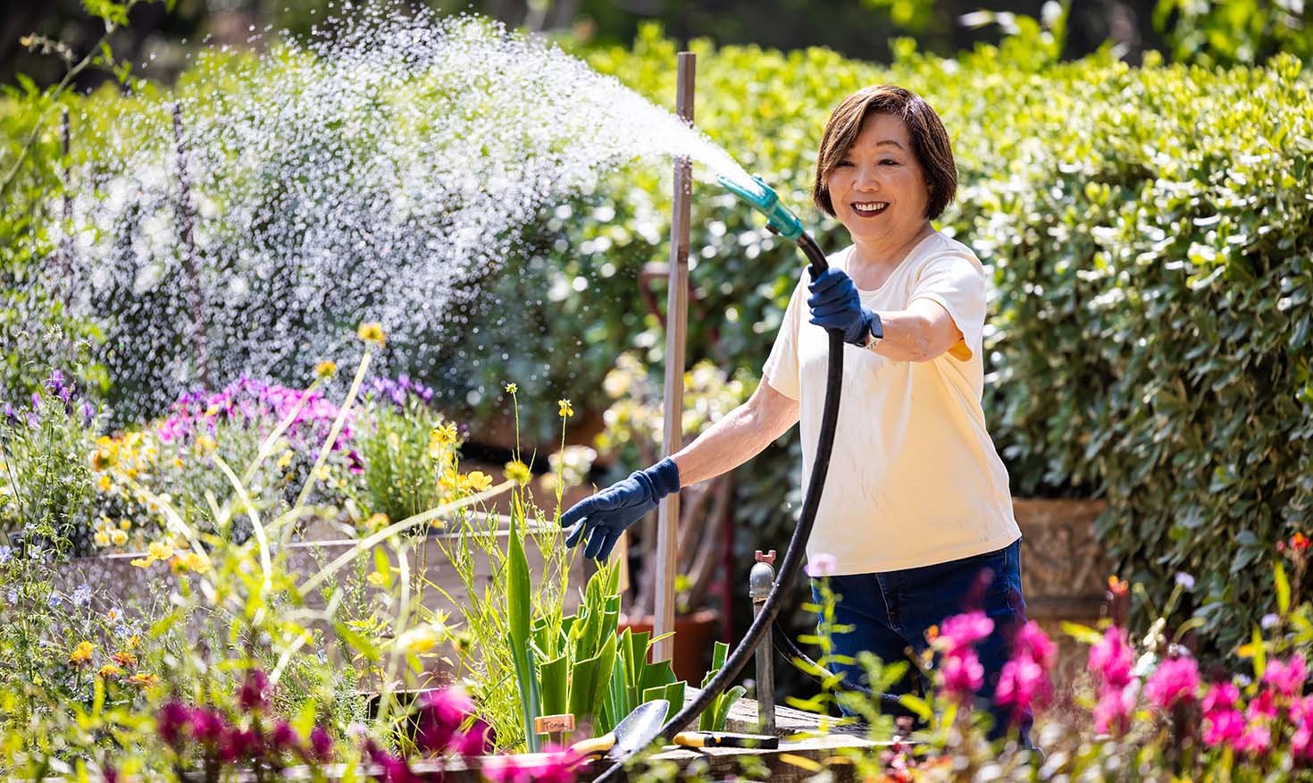 Senior woman watering flowers in the Royal Oaks gardens