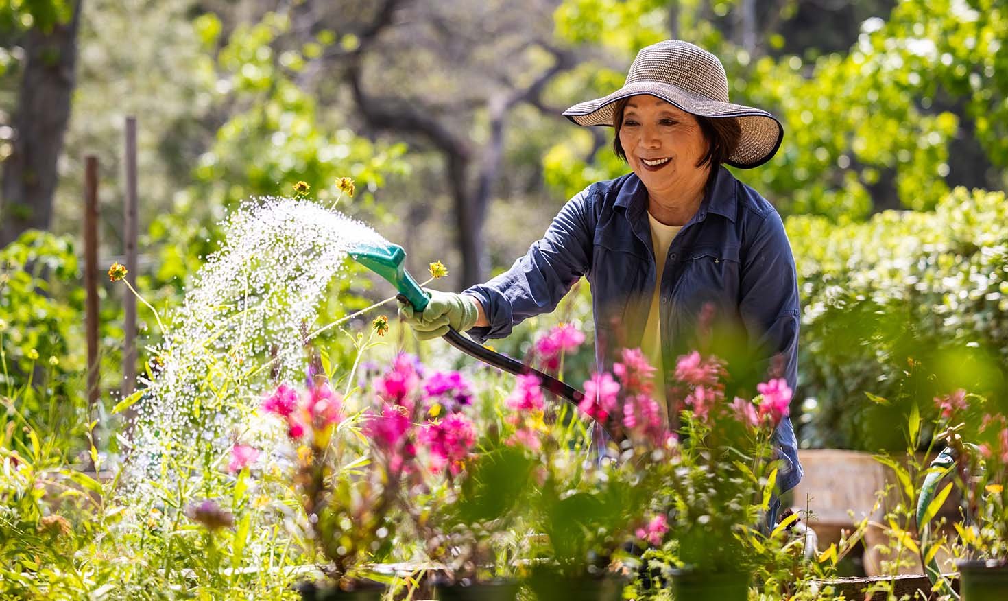 Senior woman watering flowers in the Royal Oaks gardens