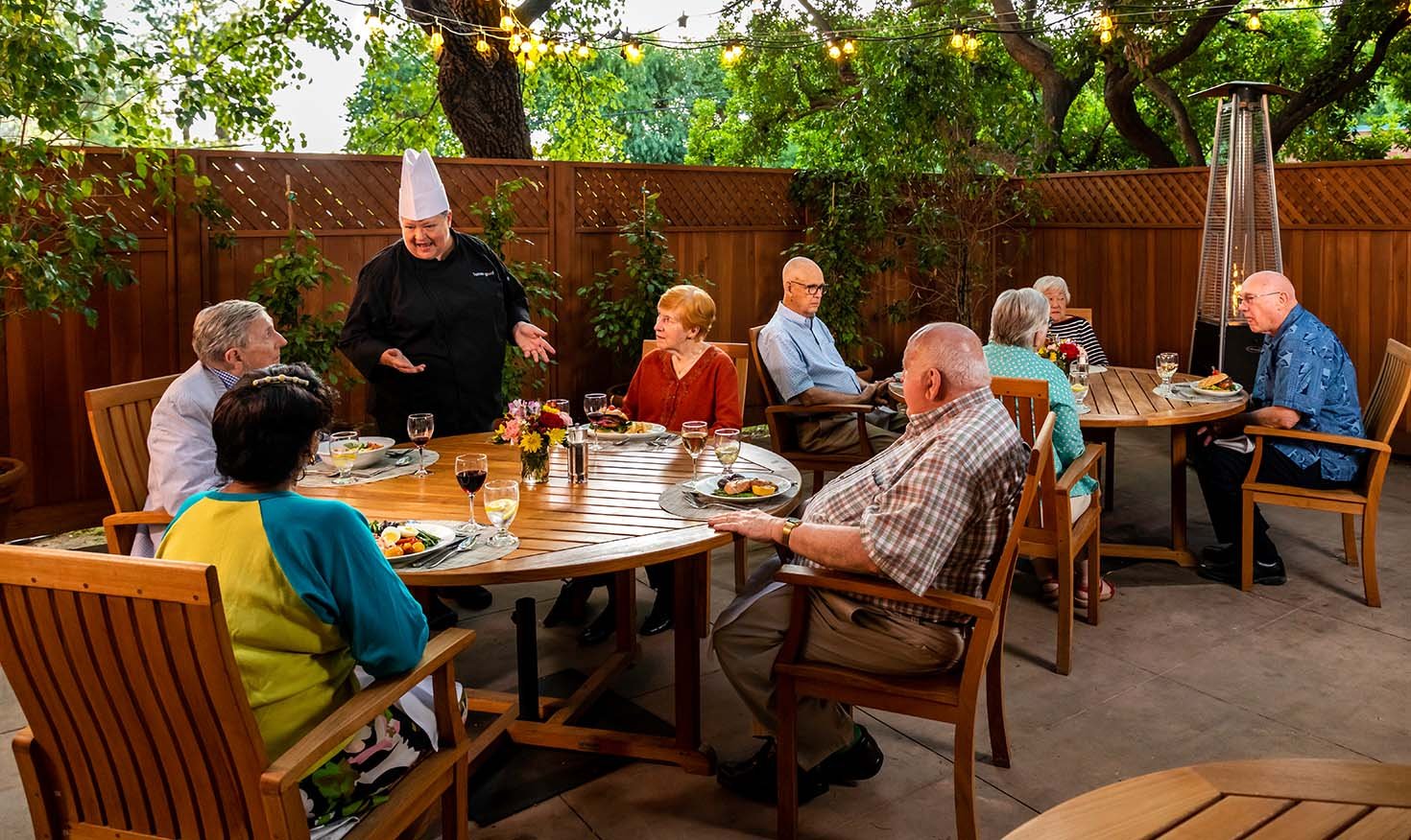 Royal Oaks chef speaking to a table of seniors dining on the patio at Royal Oaks