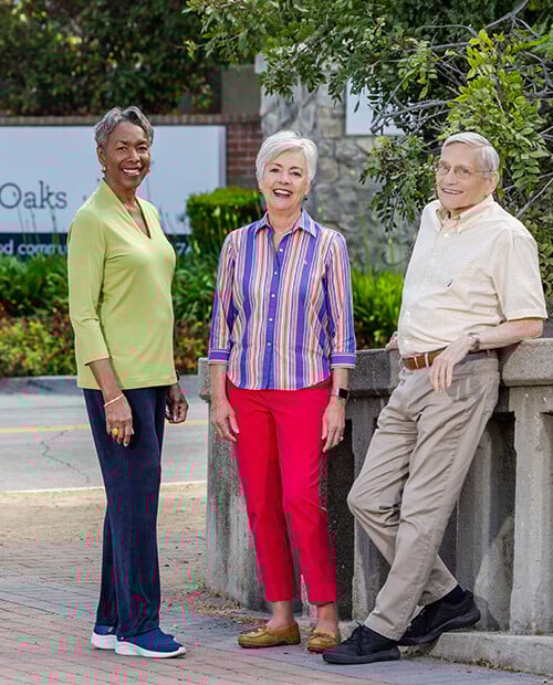 Two senior women and a senior man standing at the entrance to Royal Oaks