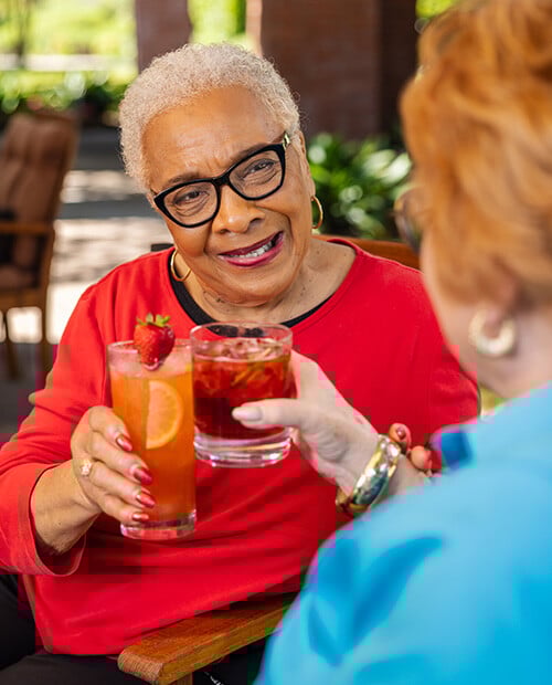 Two senior women toasting with cocktails