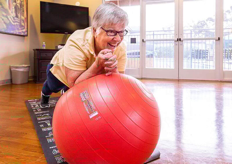 Senior woman using big red exercise ball in the fitness center