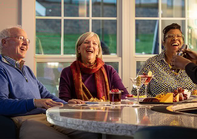 Three smiling seniors with a drink at a bar