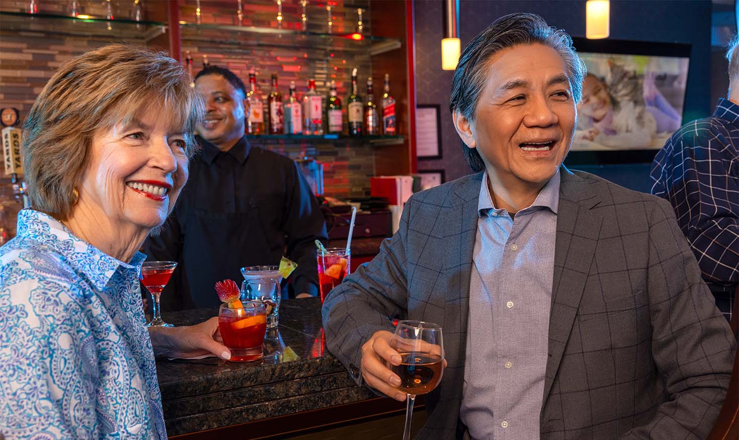 A senior man and woman enjoying drinks at a bar