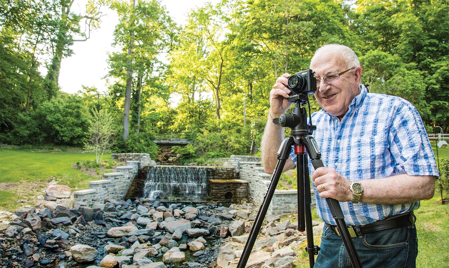 Senior man taking photos outdoors with a camera on a tripod