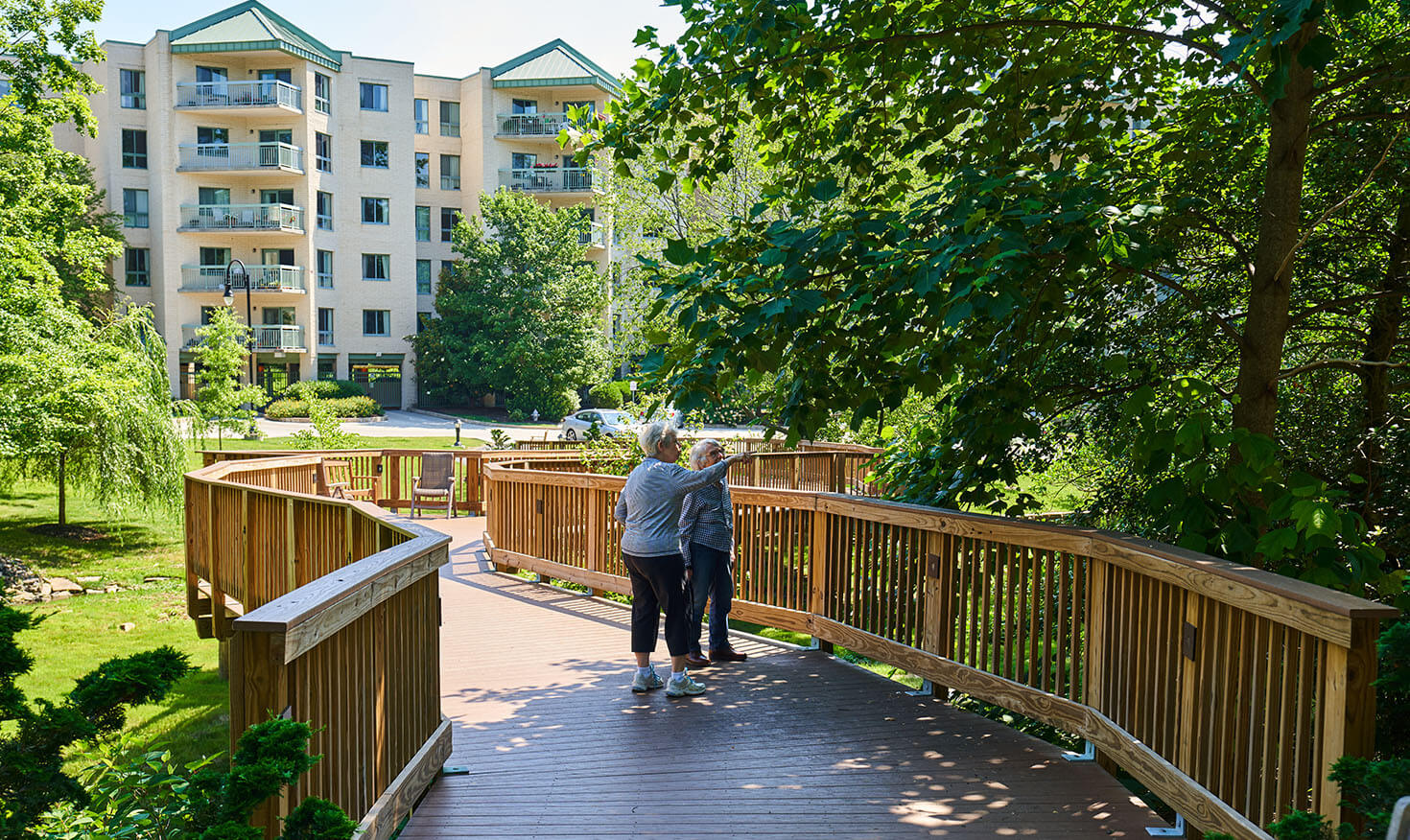 Two seniors walking along a wooden bridge in the community