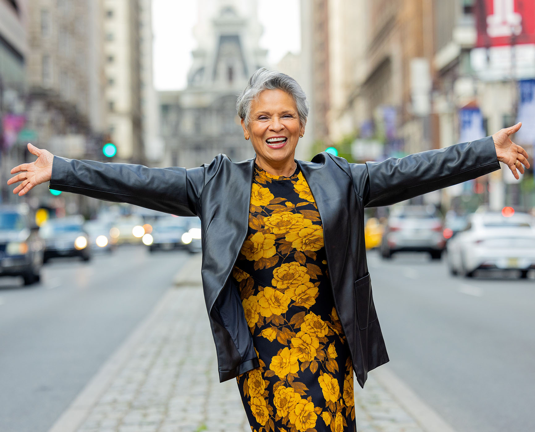 Senior woman with her arms spread wide in a city 