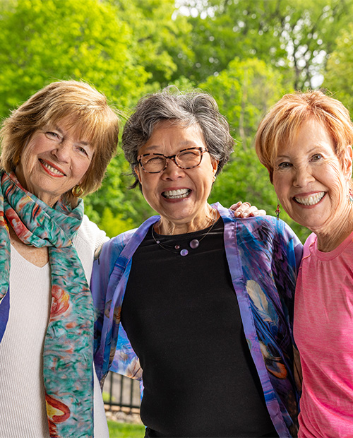 Three smiling senior women standing outside